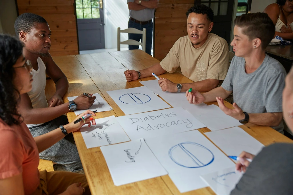People collaborate on diabetes advocacy designs at a table.